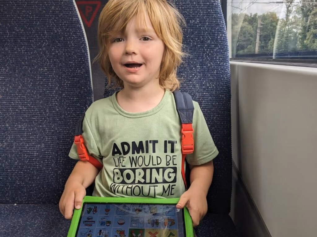 Oliver sitting on a train holding a tablet.