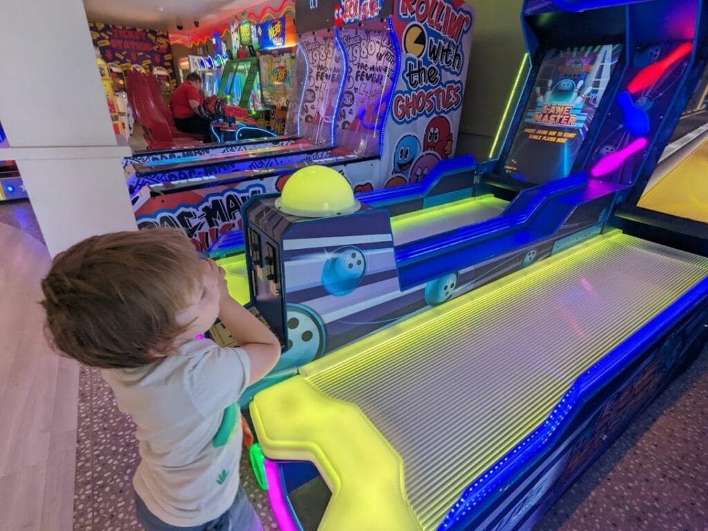 Oliver playing an arcade bowling game with bright neon lights.