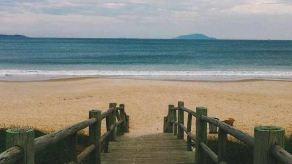 A sandy beach with the sea and mountains in the distance.